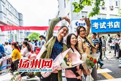 三名考生考场外“比心”，庆祝高考落幕。张卓君摄