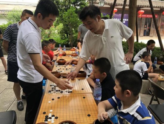 职业三段王鹭（左）和市围棋协会会长周林在为小选手讲棋