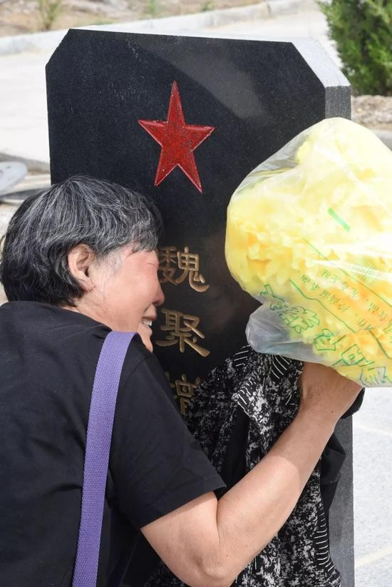 魏聚增的姐姐在墓碑前痛哭。受访者供图