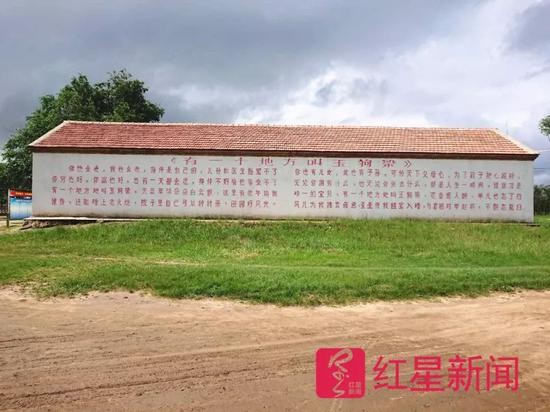 ▲村里一面墙上印着卢文震编写的村歌《有一个地方叫玉狗梁》  图片来源：红星新闻