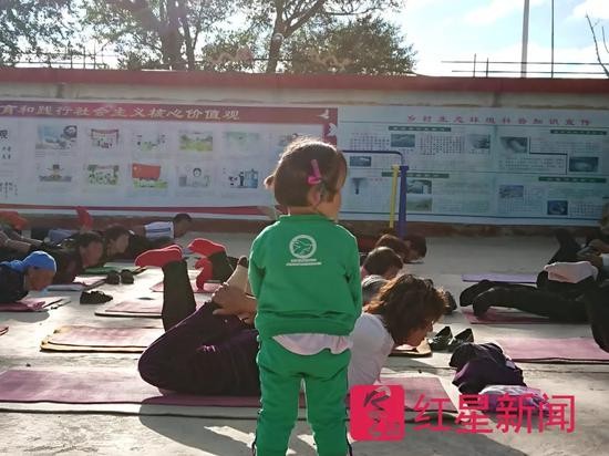 ▲一个小孩在围观大人们练瑜伽  图片来源：红星新闻