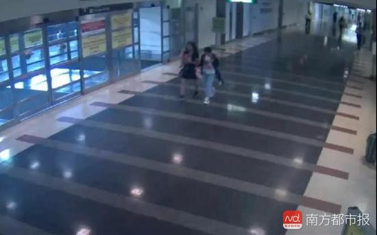 失踪女孩和女嫌疑人一起走到机场的“抵达”区域。