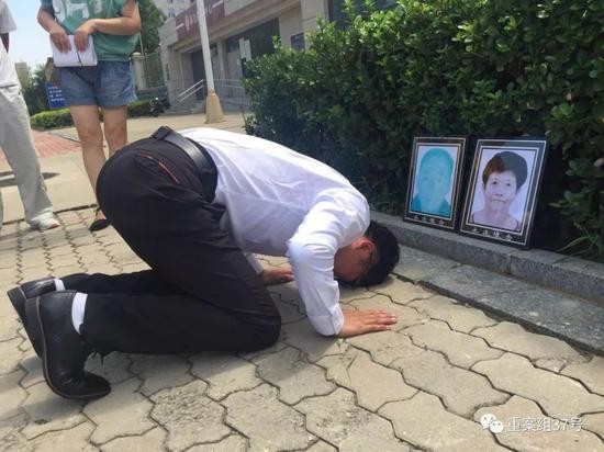 ▲获无罪后，廖海军在法院门前朝父母遗像磕头告慰。    新京报记者 赵凯迪 摄
