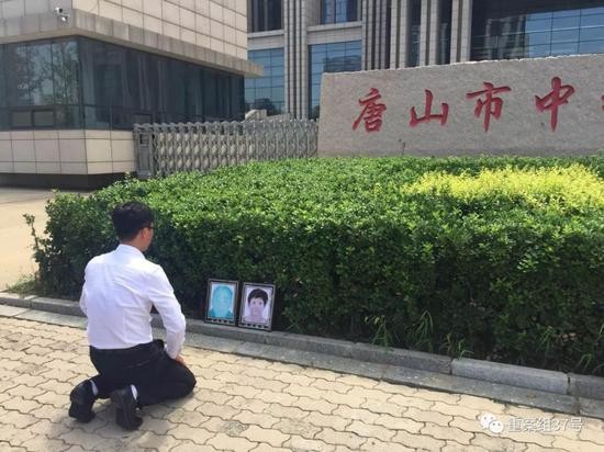 ▲获无罪后，廖海军在法院门前朝父母遗像磕头告慰。    新京报记者 赵凯迪 摄