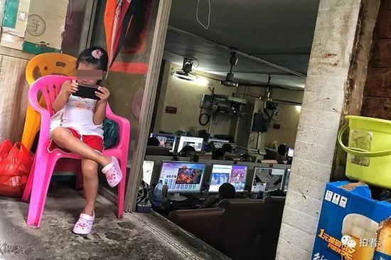 △ 三和人力市场附近的小巷中，网吧老板的孩子在门口玩手机，网吧内生意兴隆，这几天总是下雨，网吧内一位难求。