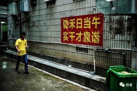 △ 早晨7点，徐家穿过窄巷，准备去找当日的工作。三和人力市场附近的窄巷中挂了许多的励志和警示标语。