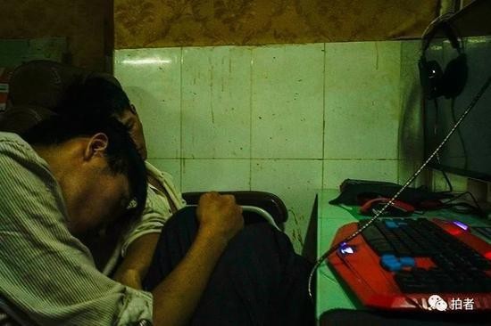 △ 网吧内，两个打工者正在座位上睡觉。他们的位置靠着厕所，很少有人选择在这里上网，是睡觉的好地方。