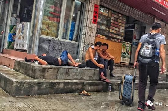 △ 下午4点，三和人力市场附近的小巷中，喝醉的打工者躺在路边，新来的打工者拖着行李从一旁走过。