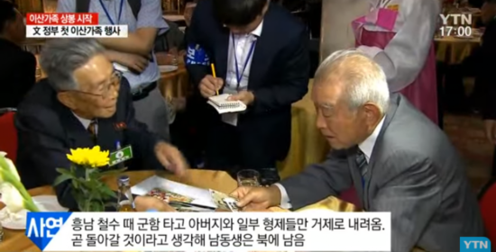 老人将相片摆满桌子，一一给亲人介绍。（韩国YTN电视台）