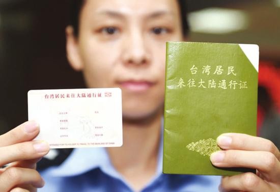 图为北京市公安局出入境管理总队的一名民警在展示电子台胞证样证（左）和本式台胞证的对比。新华社记者陈晔华 摄