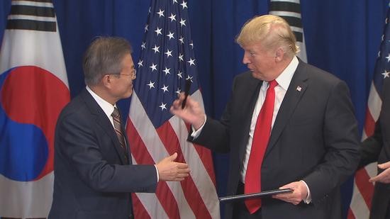 特朗普把刚刚用过的笔送给文在寅。(韩联社)