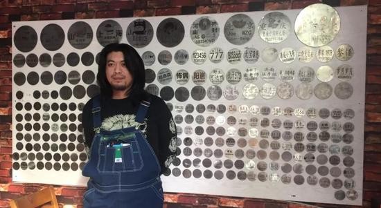 耿帅站在粉丝墙前，身后是为他打赏的粉丝名单圆牌。新京报记者赵蕾 摄