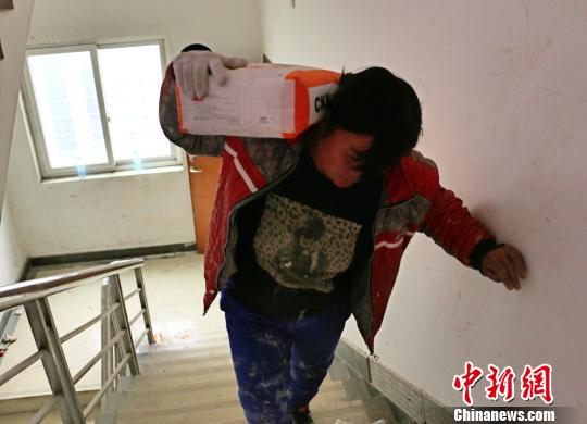 图为盛桂真扛涂料。　夏莹 摄