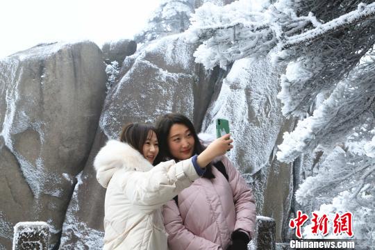 游客置身冰雪世界，与黄山雪合影留念。　汪钰 摄