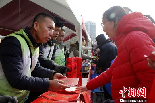 年货市集中，义工为现场观众发放春联。　李佩珊 摄