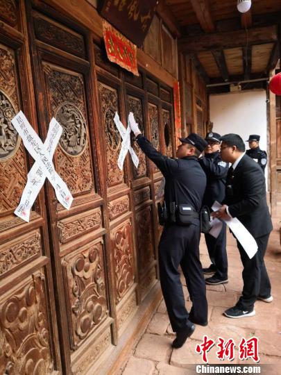 图为法院工作人员对一座涉案“古宅酒店”贴上封条。　钟欣 摄