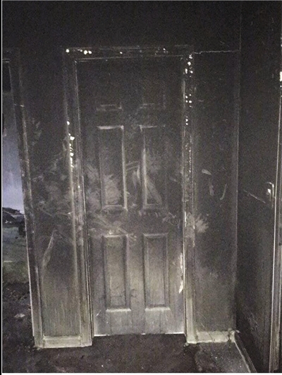 卧室门外侧(靠近火源一侧),墙壁和门已经完全被烟熏黑