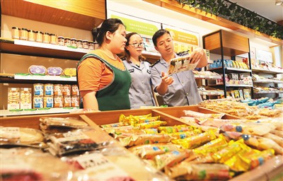 安徽省合肥市蜀山区琥珀街道市场监管科所的工作人员来到辖区校园周边的零食商店,检查商家进货票据、抽查各类小零食的外包装。陈三虎摄(人民视觉)