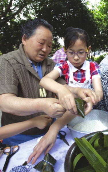　　社区老苏州教孩子们包粽子。记者　张健摄