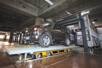 停车机器人载着托盘和上面的汽车自动驶入车库停车位。