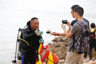 潜水搜救 刚上岸的潜水员向采访者讲述岸边搜索进展。
