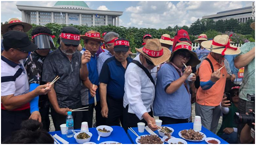  （狗农协会的多名狗肉业者当场大口吃起狗肉。图源：CNN）