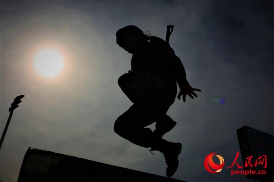 一名武警官兵快速跳跃障碍。