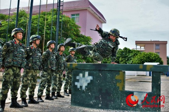 一名武警官兵身着厚重的防弹衣和头盔进行跳跃矮墙示范。