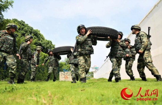 武警官兵在进行扛轮胎冲刺比拼。
