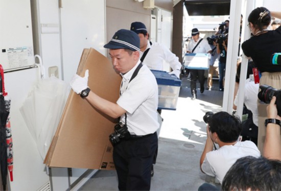 7月26日上午9点29分,京都府警方调查人员抱着纸箱进入青叶真司位于公寓一楼的住所进行搜查。(图片来源:日本《朝日新闻》网站)