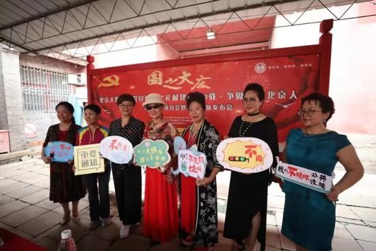 大妈队长拿着宣传标语合影留念。新京报记者 王飞 摄