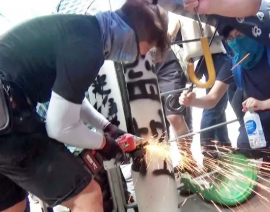 图为蒙面黑衣人竟用电锯锯开路边智慧灯柱，推倒灯柱并&ldquo;肢解&rdquo;。（来源：港媒）