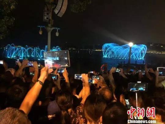 游客用手机记录下西湖音乐喷泉的美丽瞬间。孙妮亚 摄