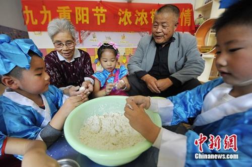  资料图：小朋友与老人共做重阳糕。 孟德龙 摄