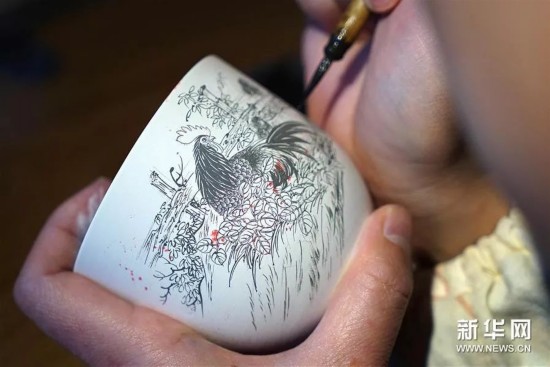 ▲工匠在瓷坯上绘制图案。（新华社）