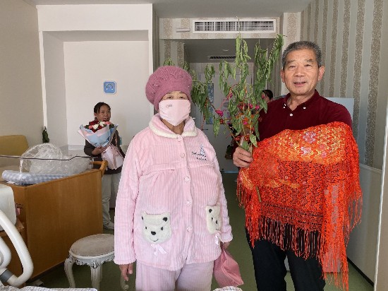 出院前，黄维平手拿桃树枝，与妻子和女儿一起拍照留念。新京报记者 祖一飞 摄