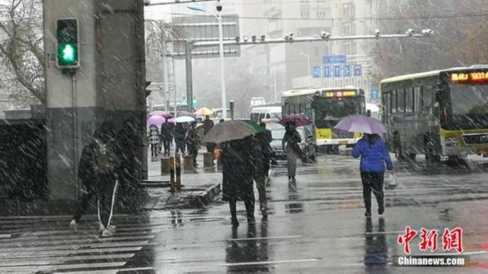 资料图：11月8日，乌鲁木齐市主城区迎来首场降雪，市民撑起雨伞出行。王小军 摄
