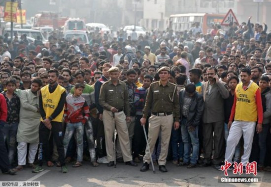 当地时间12月8日，印度德里一家工厂突发大火，救援现场烟雾弥漫。据报道，当地消防当局证实，该事故死亡人数升至43人。当地消防部门接到报警电话，随后赶到现场救援。目前，已救出56人，救援活动仍在继续。图为着火工厂附近围观的人群。