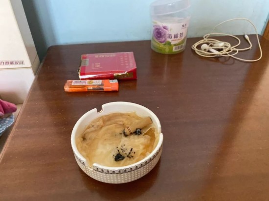  吴德宏的床前柜上摆着玻璃烟灰缸，里面留有一只南京烟的烟蒂。新京报记者祖一飞 摄