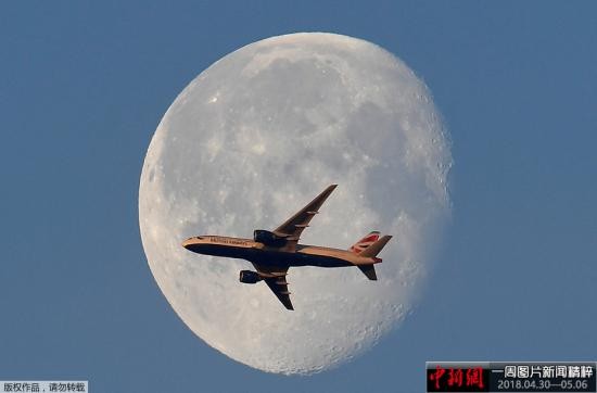 当地时间5月3日,伦敦上空明月高悬,一架英国航空的客机从月亮前飞过。