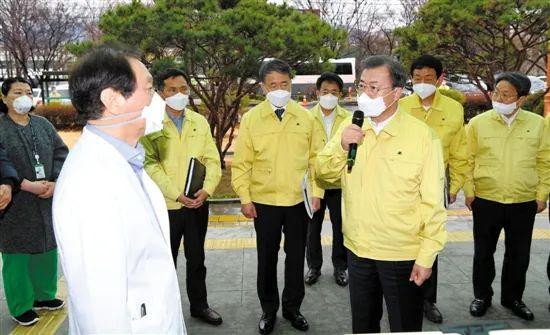 25日,韩国大邱,总统文在寅(前右)与当地医务人员交流。来源:新华社