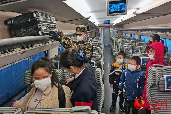 下士张新行把失明妇女和她的3个孩子送上返乡列车。