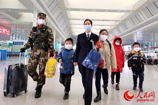 下士张新行帮助一名失明妇女和她的3个孩子取票登车。