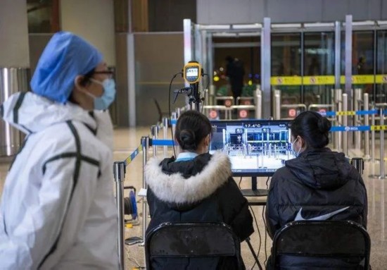 北京首都国际机场,防疫人员和工作人员通过体温检测设备对抵京旅客进行体温检测