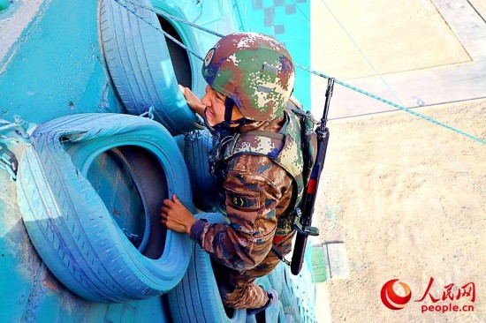 一名特战队员正在借助轮胎墙上爬。
