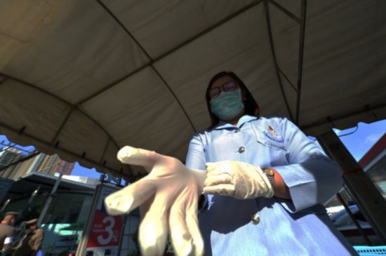  近日，在泰国曼谷，一名检查站工作人员穿戴防护用品。新华社发