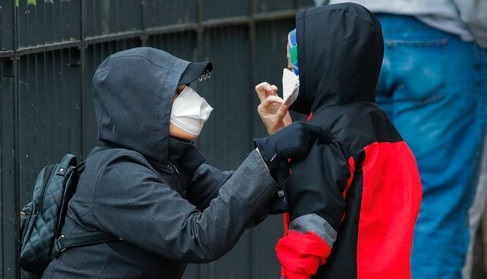 纽约街头一名女性在为孩子调整口罩(美国有线电视新闻网网站)