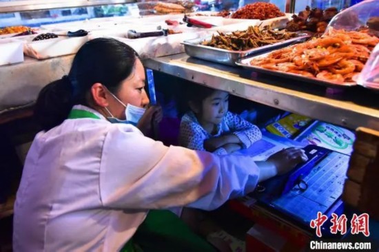  赵玮玮在生意间隙给女儿辅导功课 杨威 摄