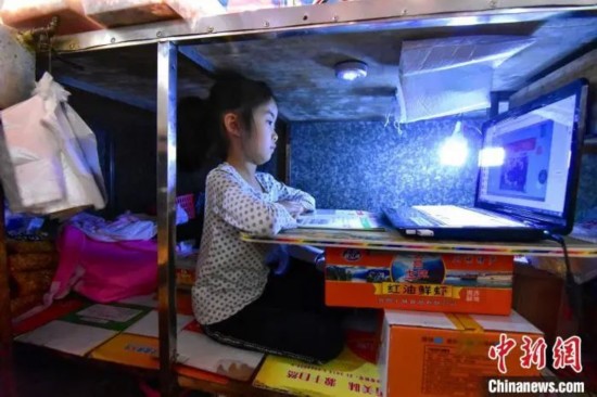 7岁的柯恩雅在卤菜铺案板下上网课 杨威 摄