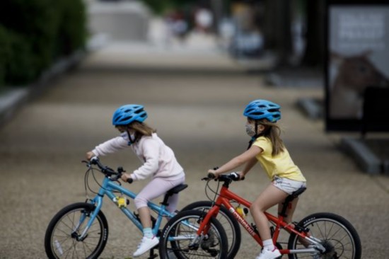 5月18日，两名美国儿童戴着口罩在骑车。新华社发